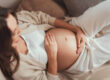 Schwangere Frau formt mit ihren Händen ein Herz über ihrem Babybauch – Symbol für Liebe und Vorfreude auf die Geburt.