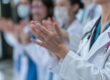 Gruppe von Ärzten und medizinischem Fachpersonal klatscht, symbolisch für Teamarbeit und Anerkennung im Gesundheitswesen.