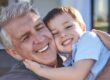 Lächelnder Großvater umarmt seinen Enkelkind, beide wirken glücklich und entspannt im Freien – Fokus auf Familie und generationsübergreifende Beziehungen