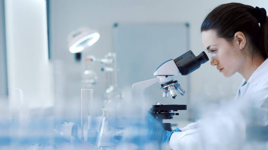 praeeklampsieforschung Wissenschaftlerin im Labor untersucht eine Probe unter einem Mikroskop, umgeben von Laborgeräten – Fokus auf Forschung und Analyse.